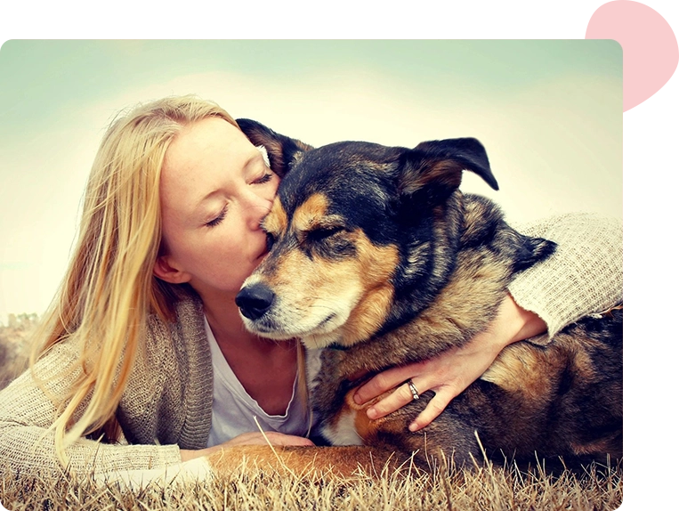 A woman resting her head against her German shepherd in a sunny field